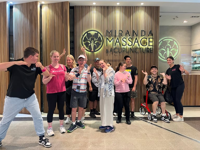 Group of people posing in front of a massage business storefront with wood paneled wall and signage