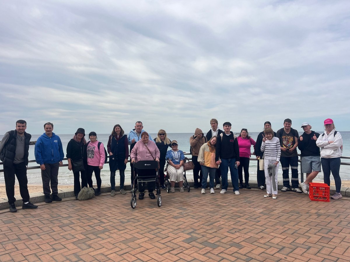Group of people standing on a boardwalk near the beach