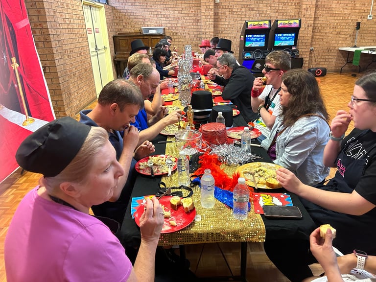 Group of people eating and socializing at tables in a brick-walled venue with arcade games visible in the background