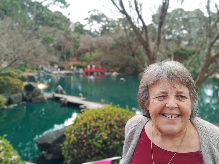 Woman smiling at camera with green lake and trees in background