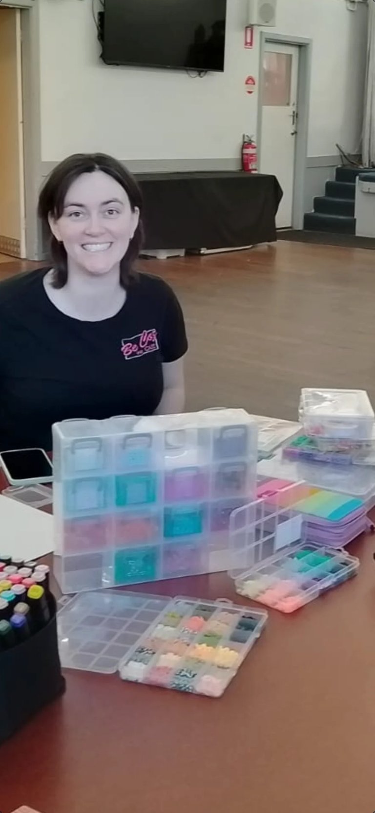 Woman smiling at table with organized craft supply containers and storage boxes in community room