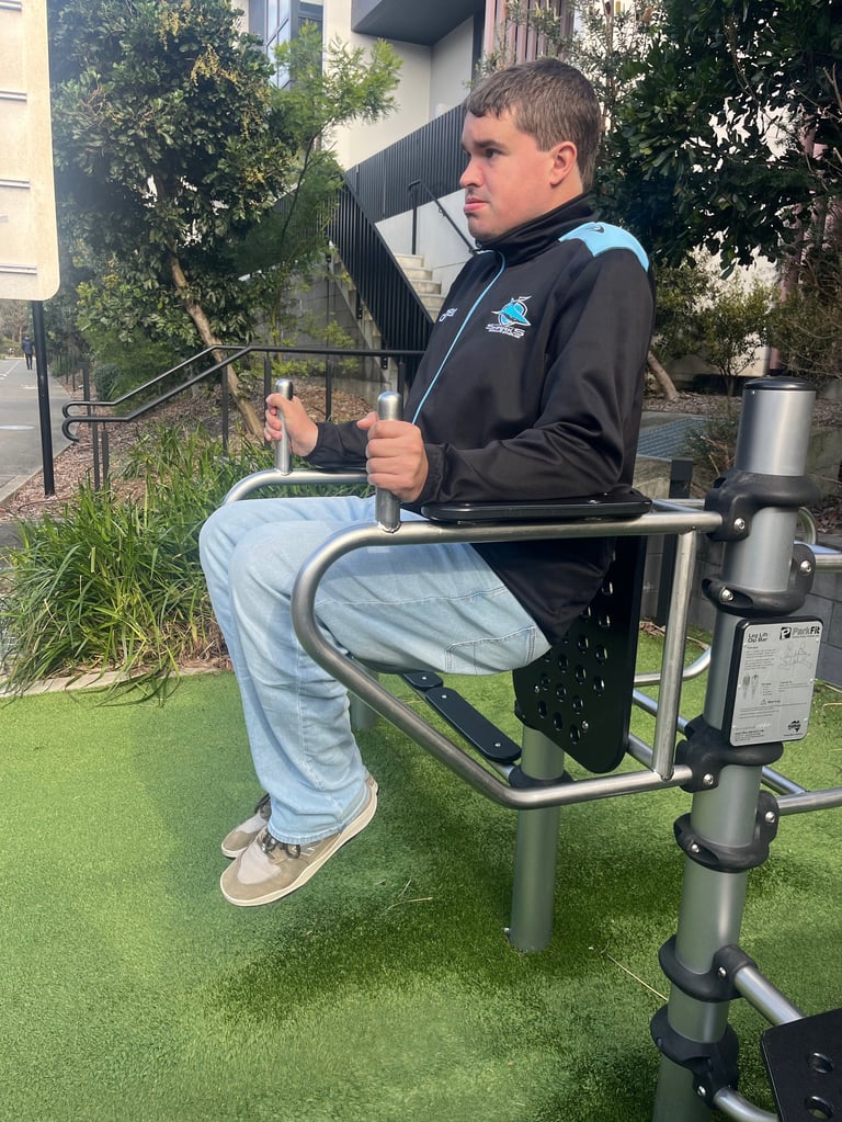 Man in black jacket using outdoor leg press exercise equipment in a park setting